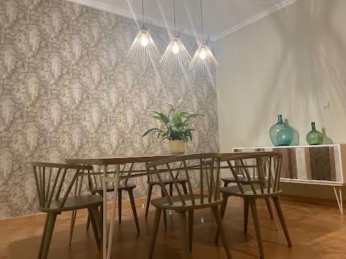 Comedor con mesa de madera, lámparas colgantes y pared de papel pintado