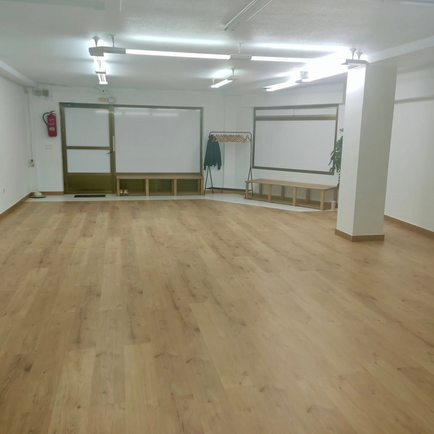 Sala diáfana con suelo de madera y zona de entrada con banco
