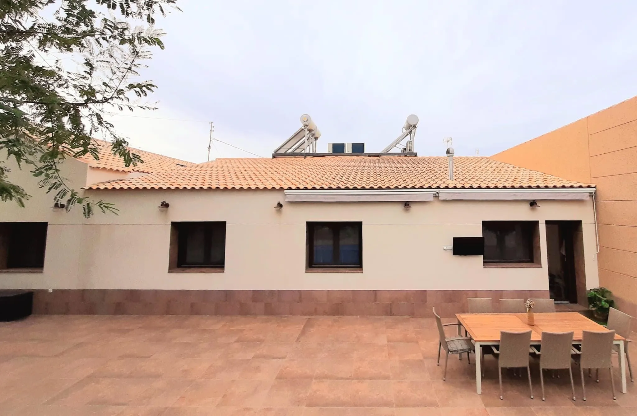 Vista general de la vivienda desde el patio, con la cubierta de teja y la mesa exterior