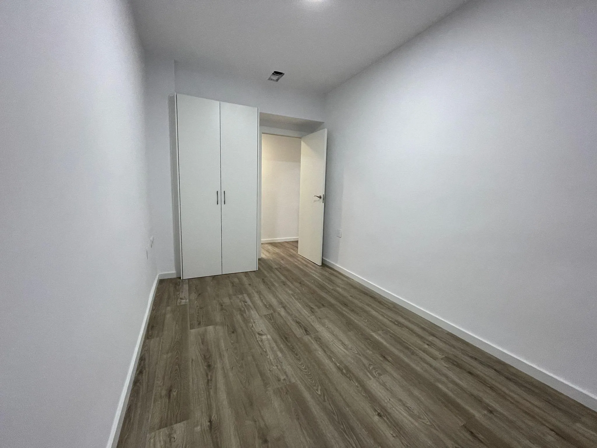Estancia con armario empotrado blanco y suelo laminado