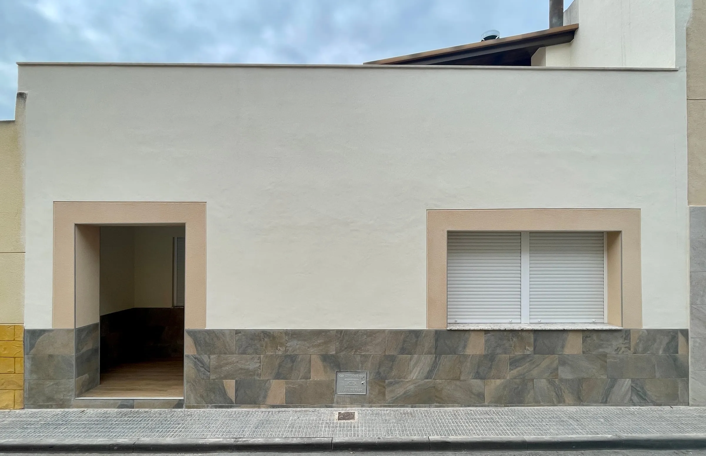 Fachada de la vivienda con zócalo de piedra