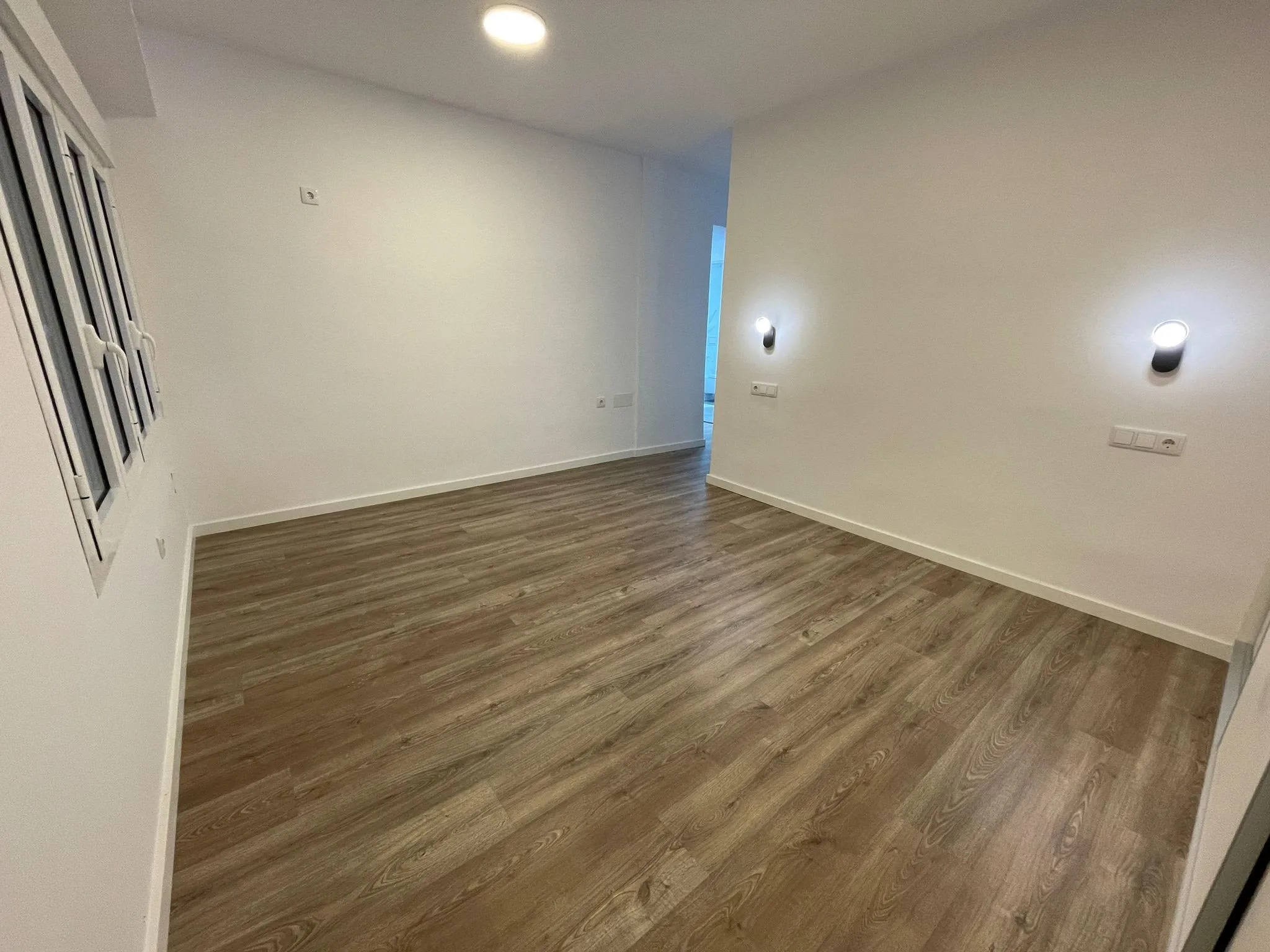 Dormitorio con ventana y suelo laminado